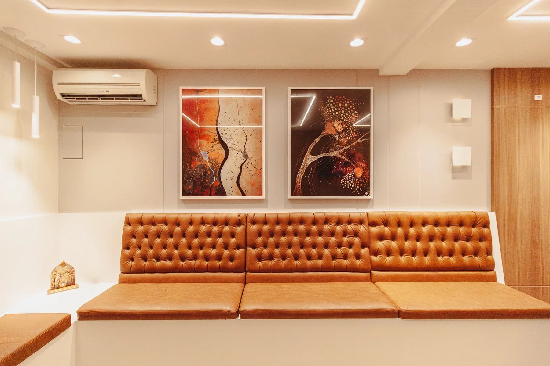 Sala de espera com estofados em tom caramelo e obras de arte